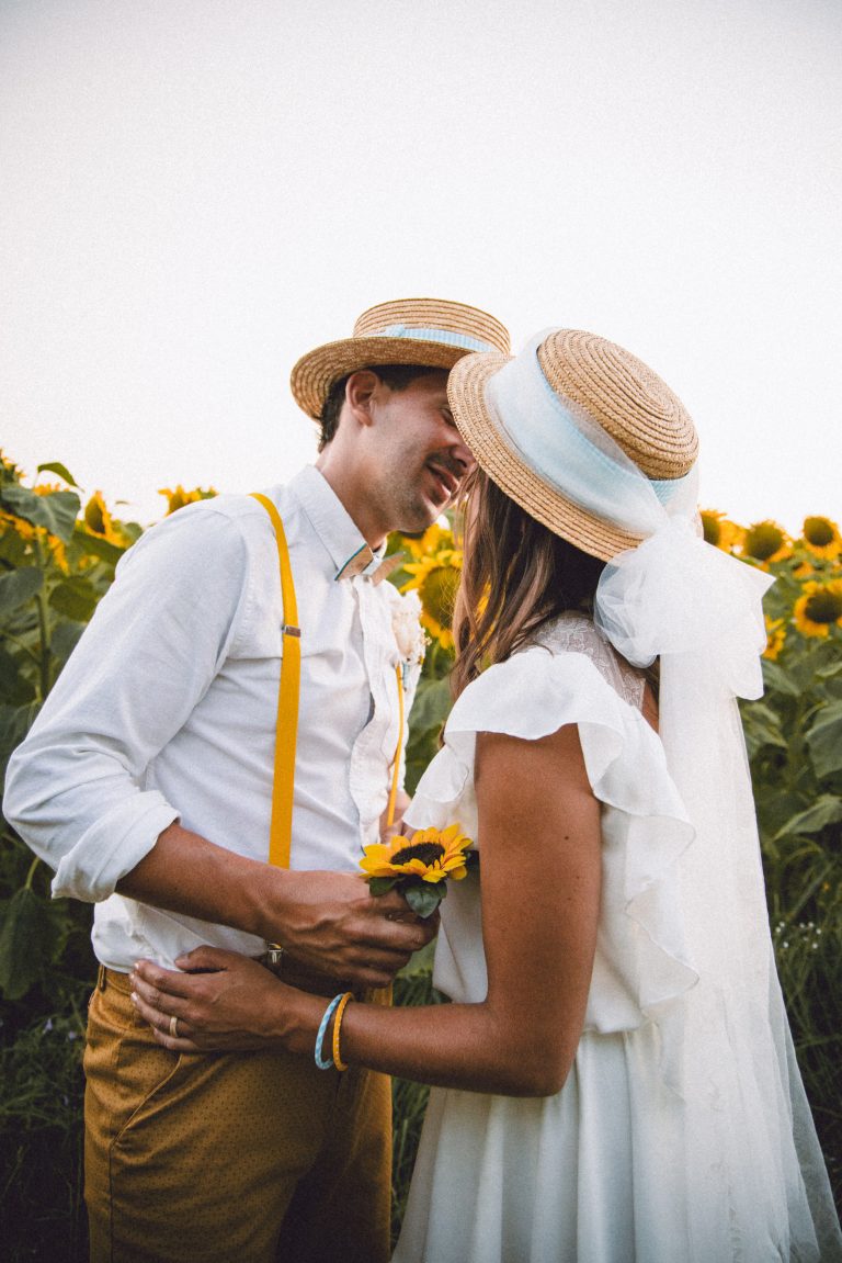 Couple célébrant leur amour dans un pique-nique champêtre entouré de tournesols.