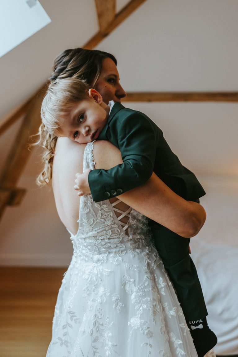 Mariée émue tenant un jeune enfant lors d'une séance photo de mariage