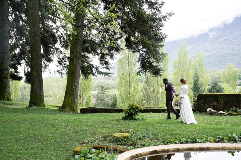 Mariés se tenant par la main dans un jardin historique, avec vue sur les montagnes