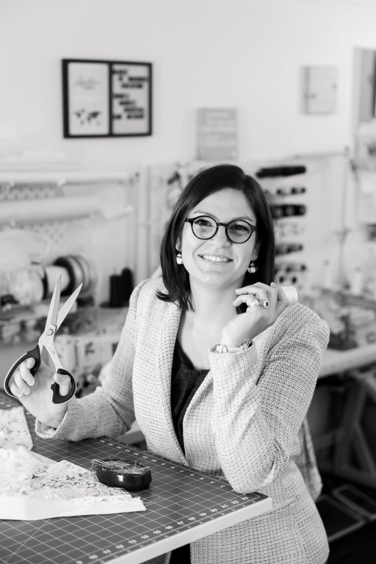 Marie de Boissieu, créatrice de robes de mariée, tenant une paire de ciseaux dans son atelier.