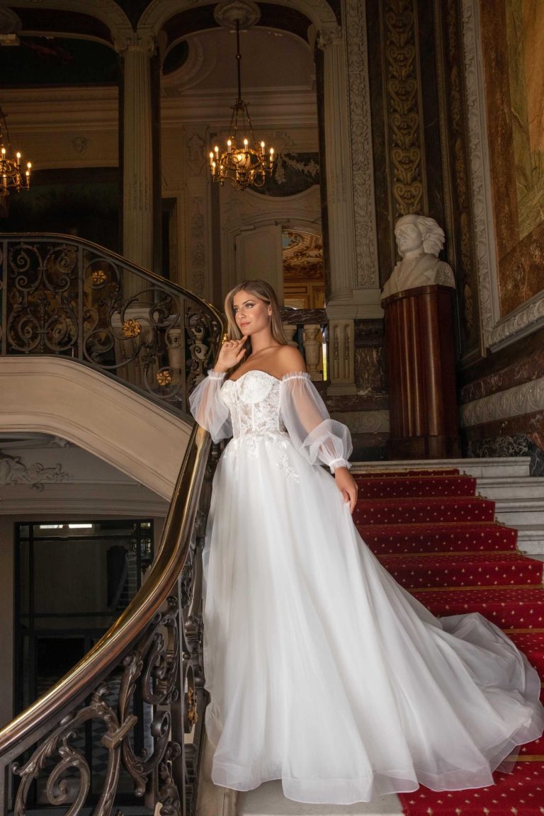 Femme élégante portant une robe de mariée avec des manches bouffantes transparentes, descendant un escalier en colimaçon dans un cadre luxueux.Femme élégante portant une robe de mariée avec des manches bouffantes transparentes, descendant un escalier en colimaçon dans un cadre luxueux.