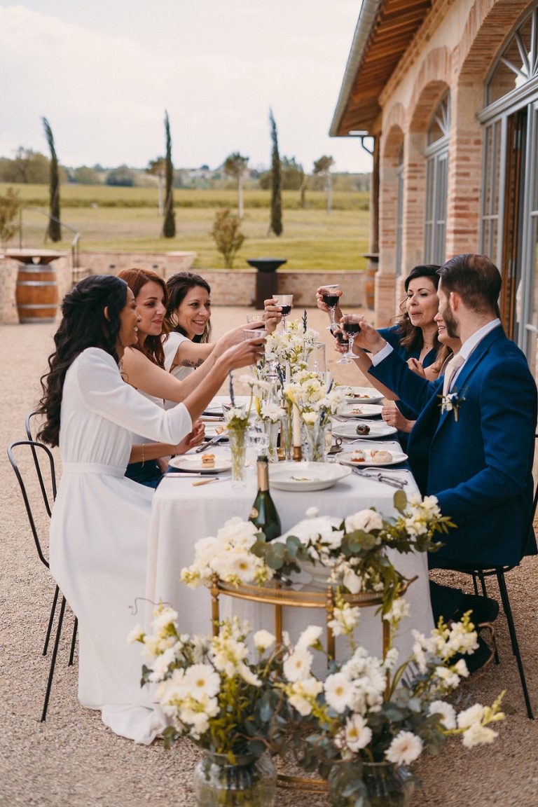 Invités trinquant autour d'une table de réception en plein air