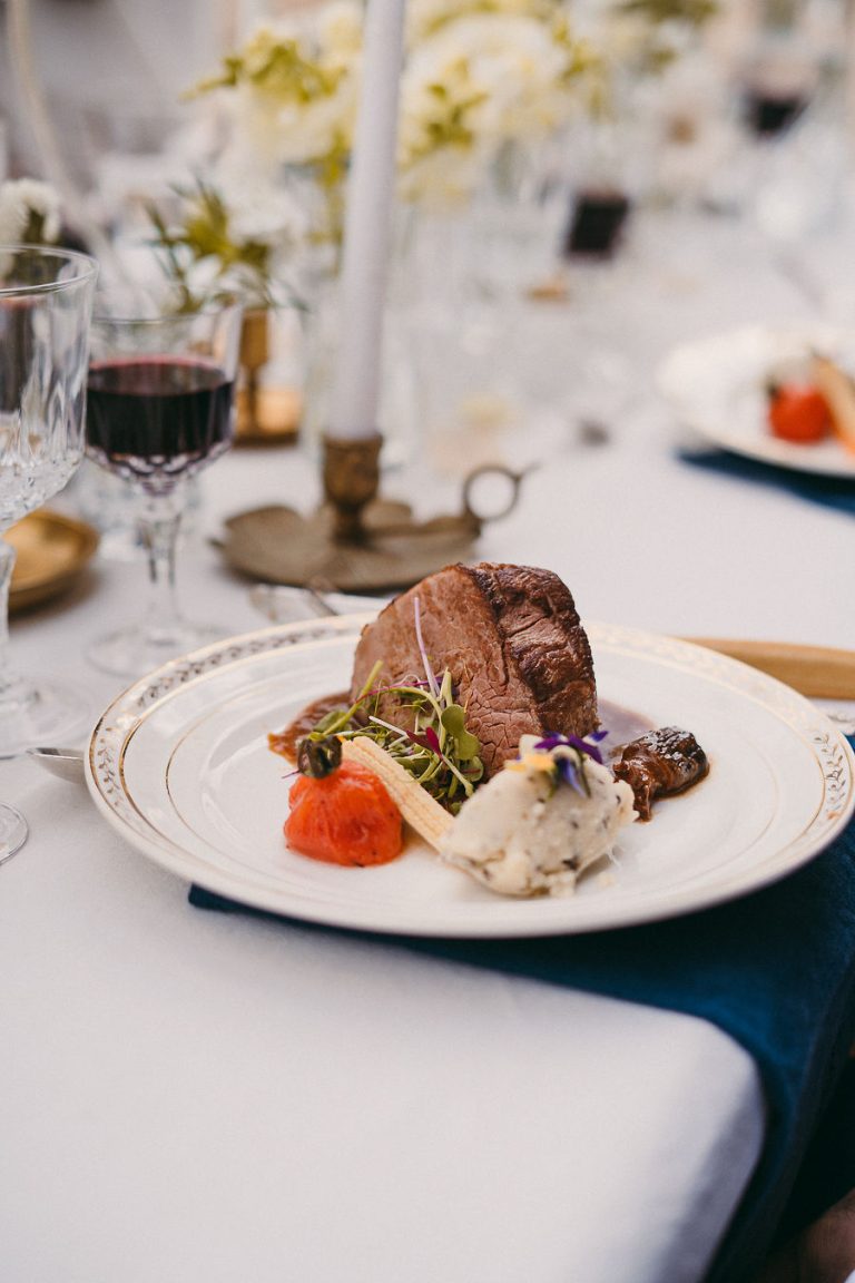 Plat principal de mariage avec viande et légumes décorés sur une table élégante