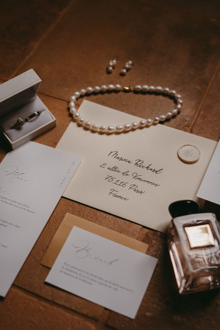 Invitation de mariage, bague et collier de perles sur une table en bois