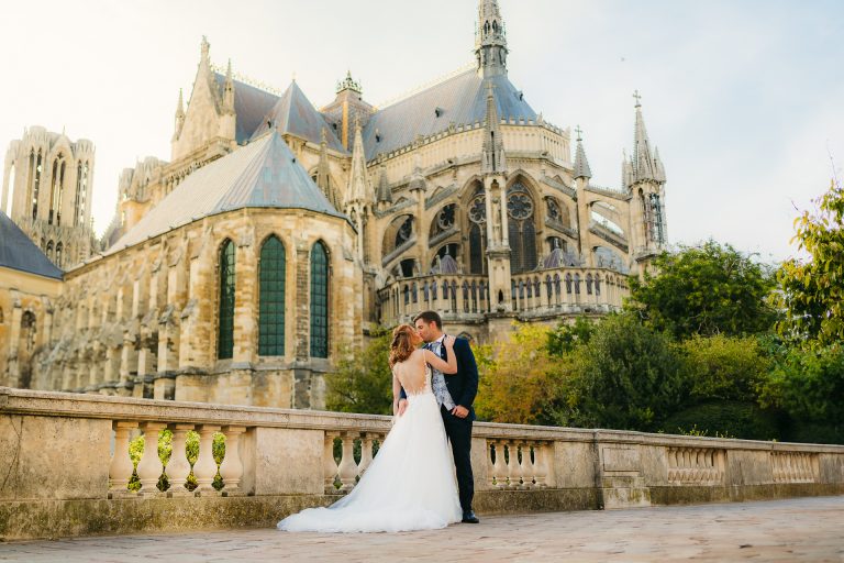 Couple de mariés posant devant une cathédrale gothique, romantisme et élégance.