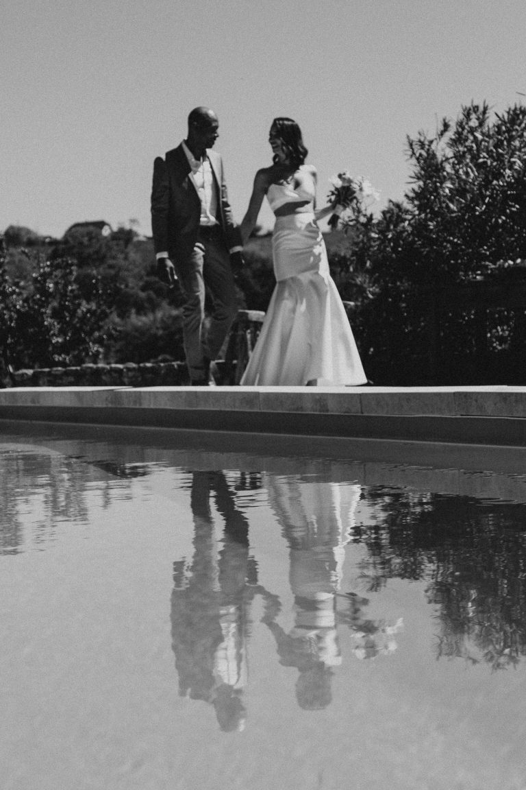 Robe de mariée sirène élégante portée par une mariée marchant près d’une piscine, capturant un moment romantique.