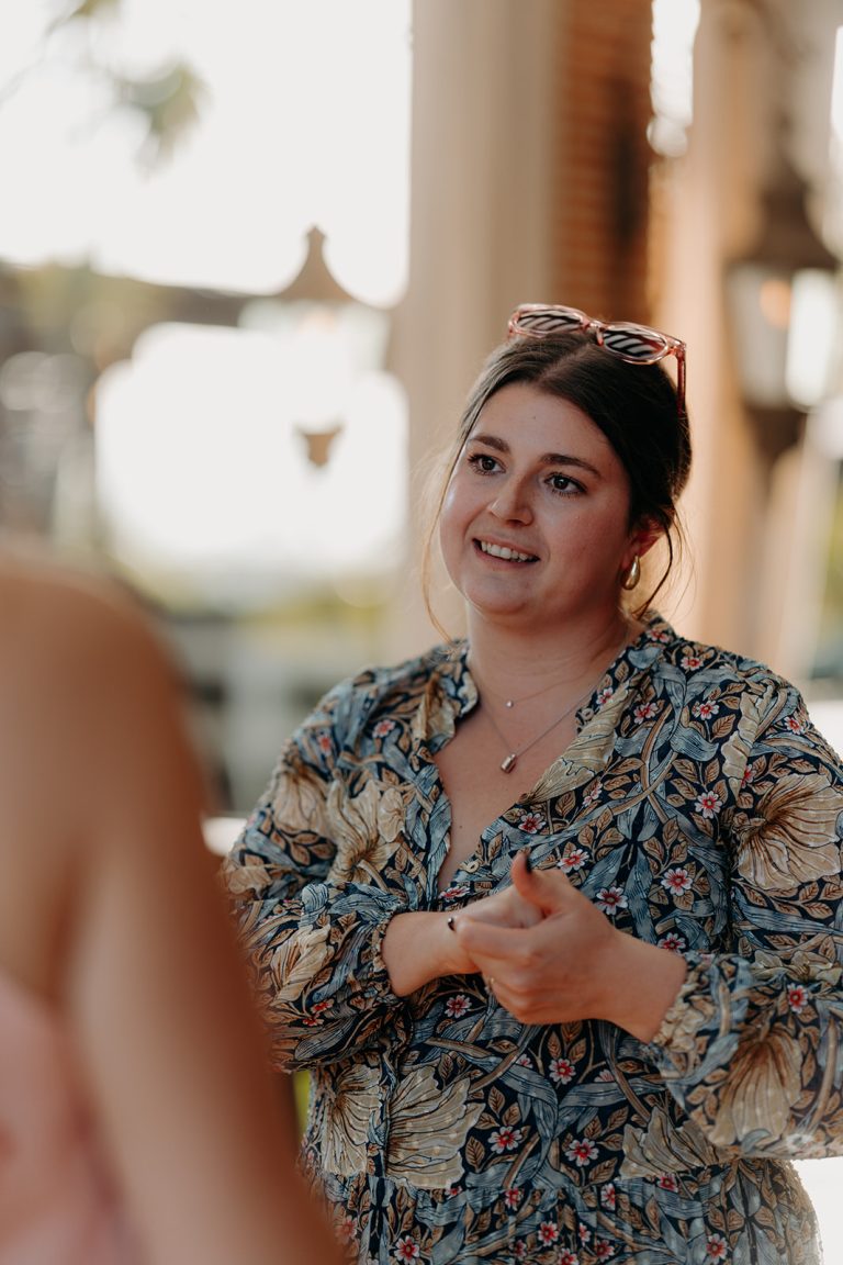 Portrait de Valentine Le Sec'h discutant avec une cliente dans un cadre lumineux, portant une blouse à motifs floraux.