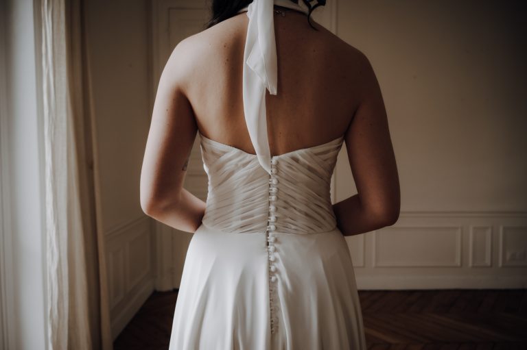 Vue de dos d’une robe de mariée sur-mesure avec des boutons élégants et un dos nu, dans un cadre parisien.