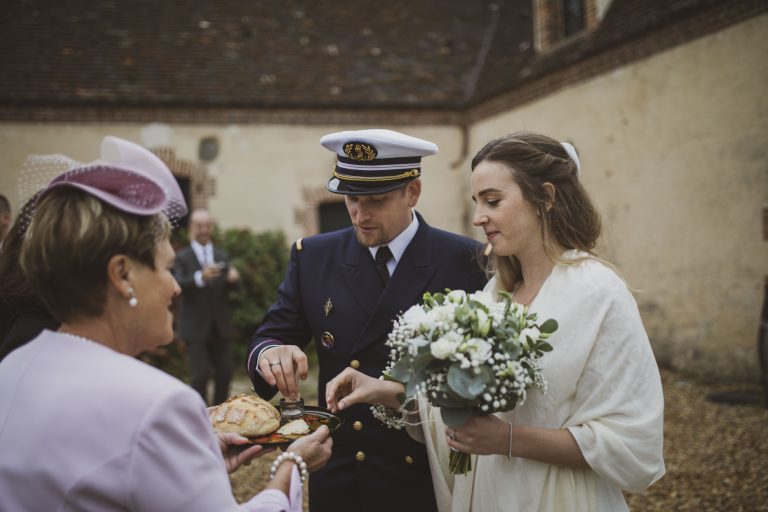 Les mariés capturés dans un moment authentique, partageant le pain traditionnel.