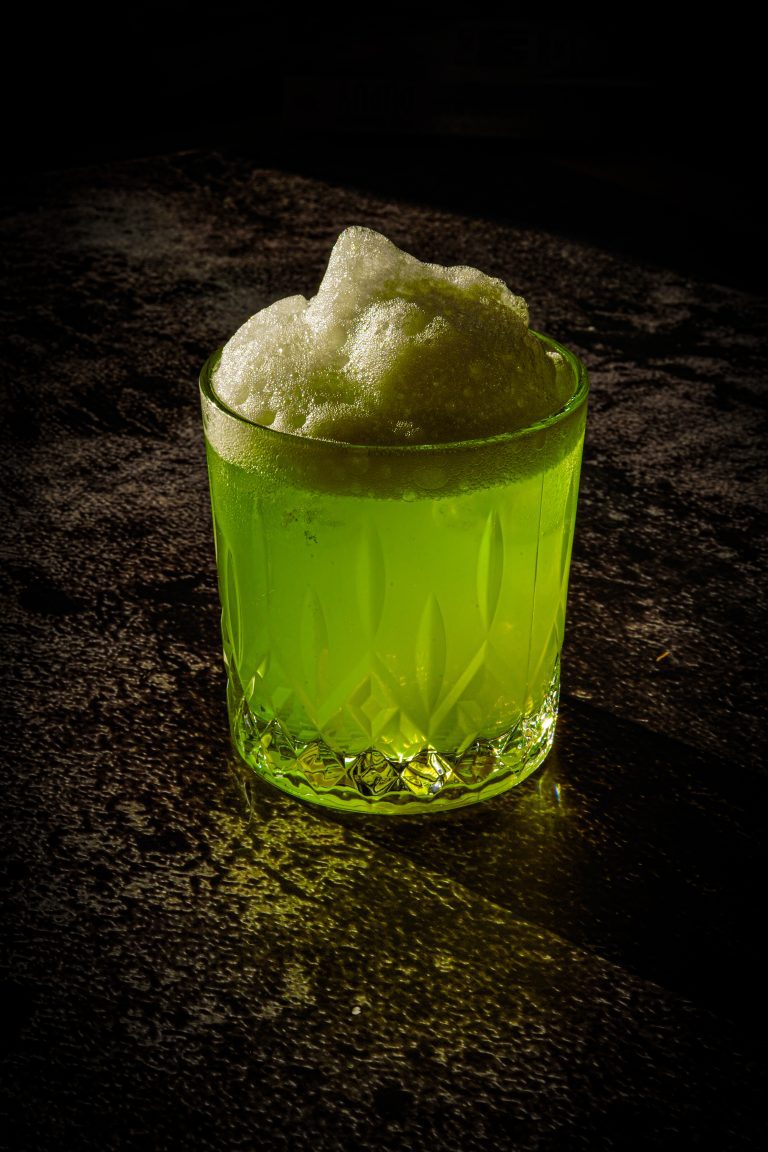 Un cocktail vert avec une mousse légère, parfait pour une réception de mariage tendance en 2025.