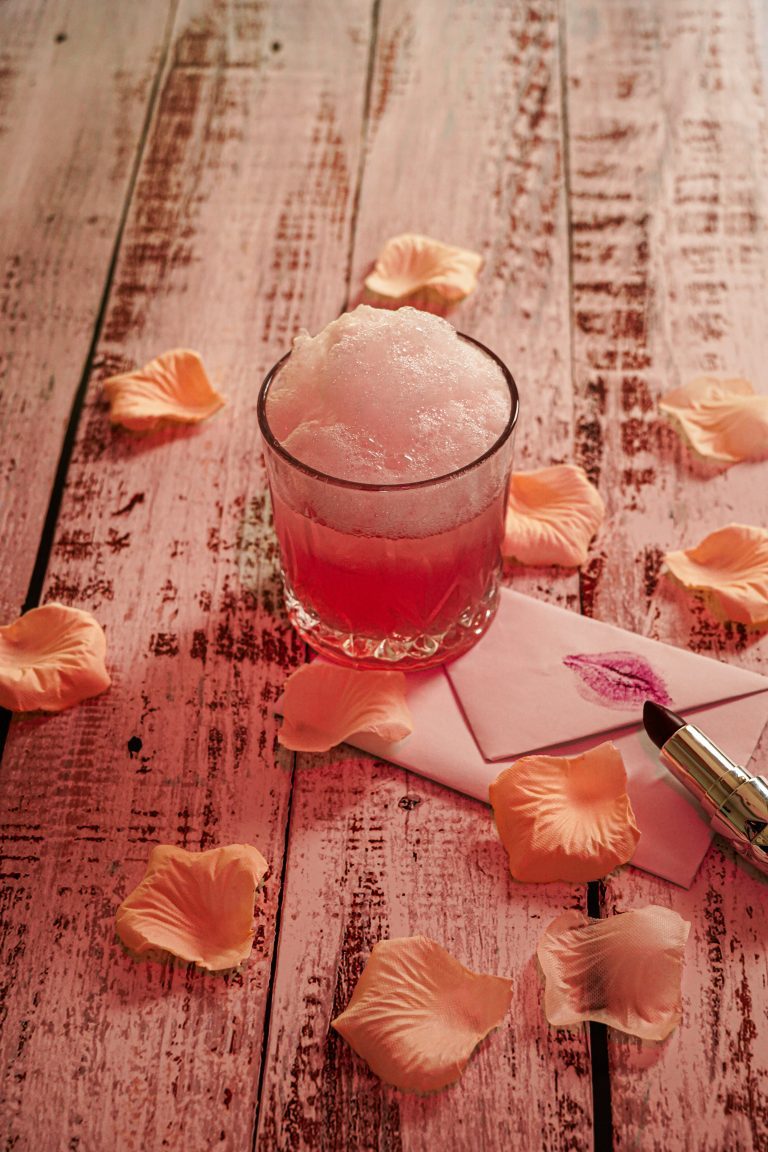 Un cocktail rose romantique décoré de mousse et de pétales, parfait pour un mariage élégant.