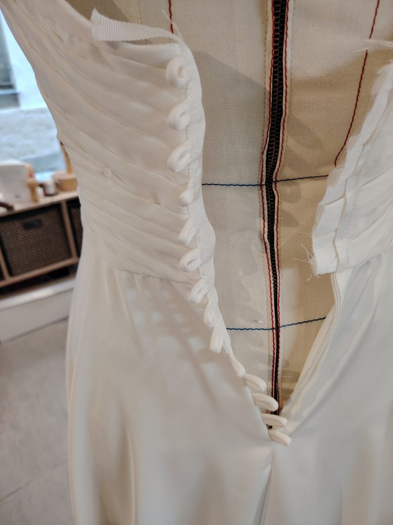 Fermeture boutonnée d'une robe de mariée sur-mesure en cours de création.